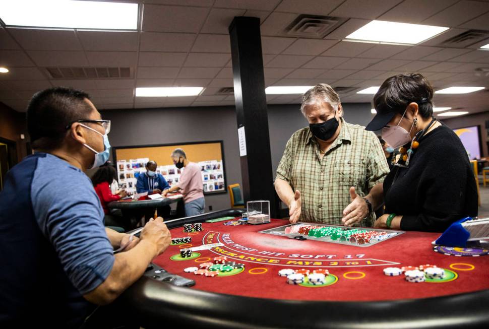 Instructor Ray Nichols, center, assists students Steven Chen, left, and Grace Ho at a blackjack ...