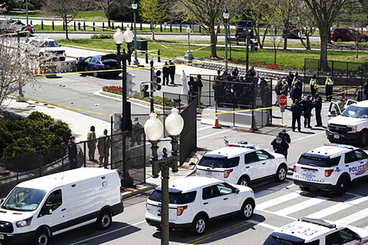 Police officers gather near a car that crashed into a barrier on Capitol Hill in Washington, Fr ...
