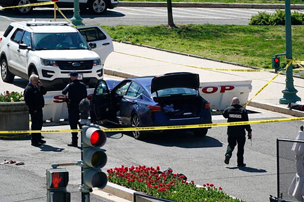 U.S. Capitol Police officers stand near a car that crashed into a barrier on Capitol Hill in Wa ...