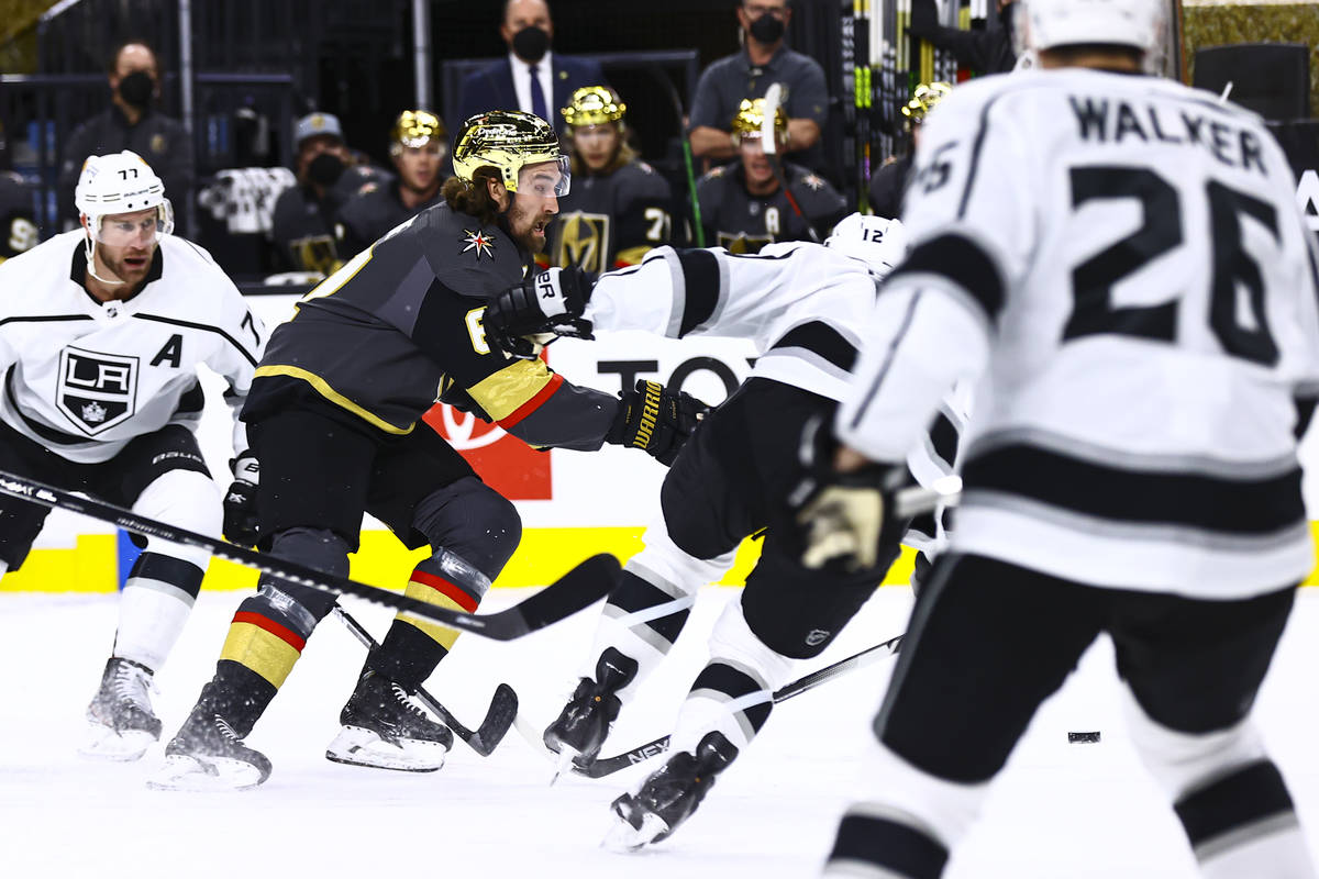 Golden Knights' Mark Stone (61) skates with the puck past Los Angeles Kings' Jeff Carter (77) a ...