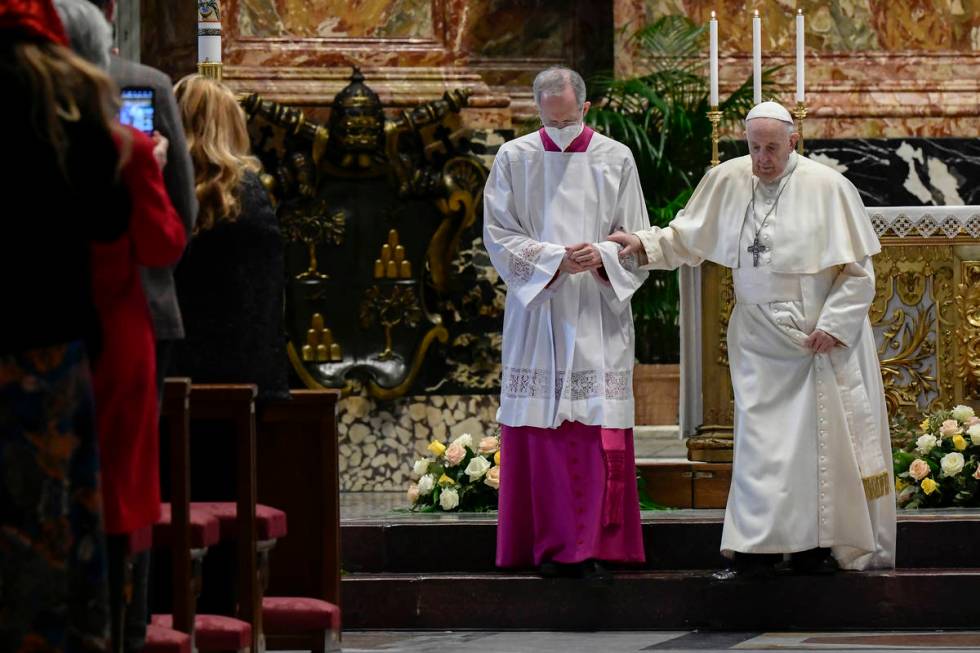 Master of Pontifical Liturgical Ceremonies, Italian priest Guido Marini helps Pope Francis step ...