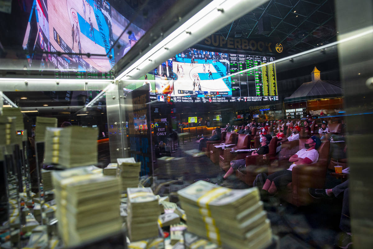 Basketball fans, framed through a promotional cash display, watch the NCAA championship basketb ...