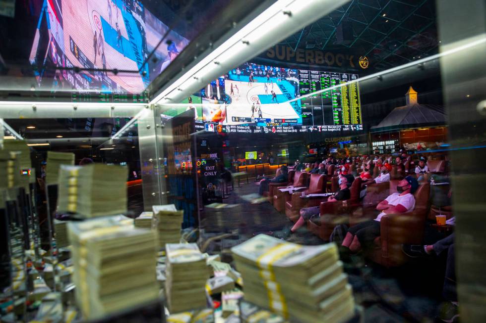 Basketball fans, framed through a promotional cash display, watch the NCAA championship basketb ...