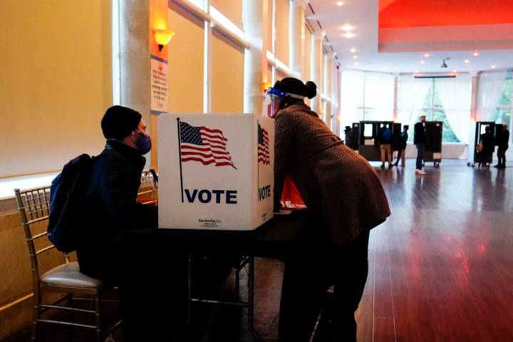 In this Nov. 3, 2020, file photo, a poll worker talks to a voter before they vote on a paper ba ...