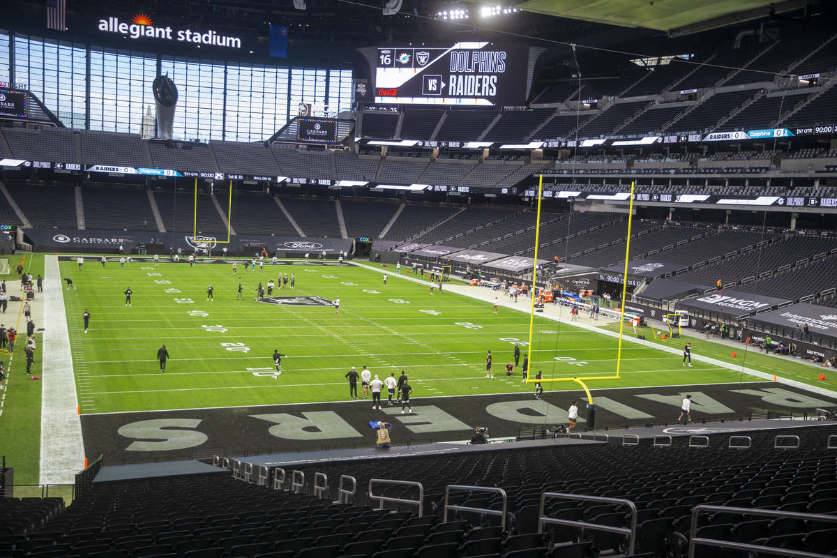 Teams warm up in an empty stadium before an NFL football game between the Raiders and the Miami ...