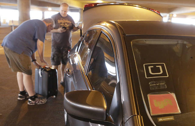 Riders prepare to load their luggage into ride-hailing companies' Uber and Lyft car at McCarran ...