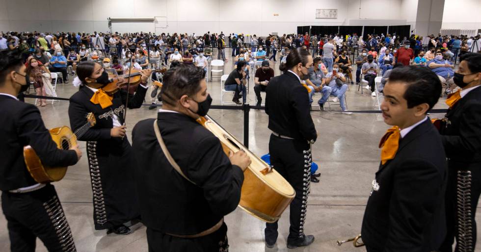 Mariachi Nuestras Raices performs to a room of people waiting in line for COVID-19 vaccines or ...