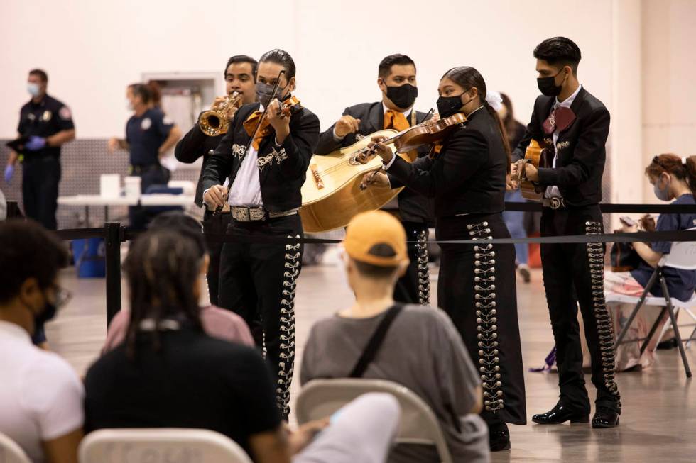 Mariachi Nuestras Raices performs to a room of people waiting in line for COVID-19 vaccines or ...