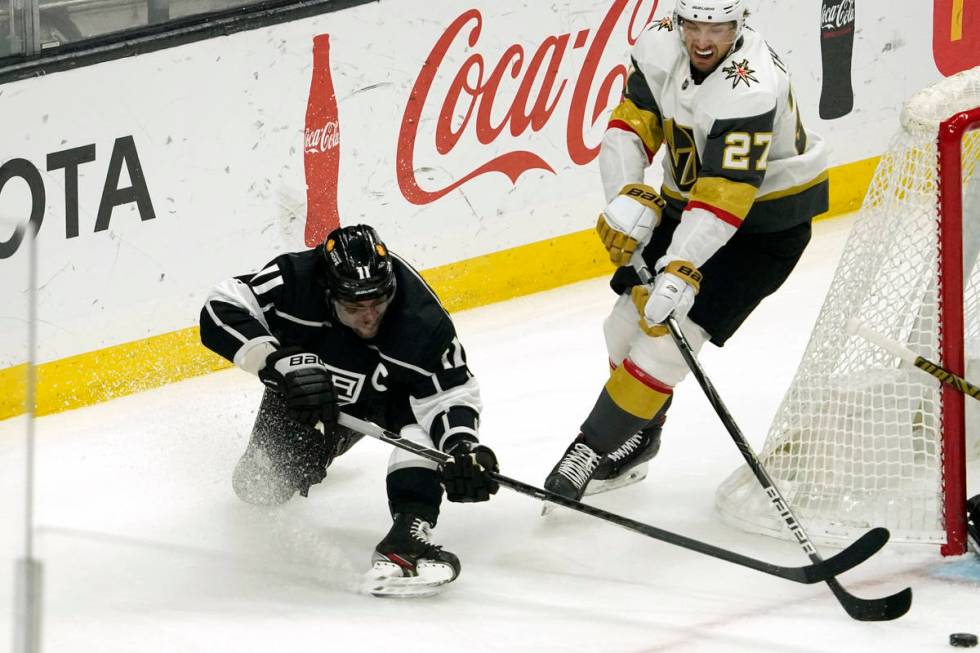 Los Angeles Kings center Anze Kopitar, left, falls as he moves the puck while under pressure fr ...