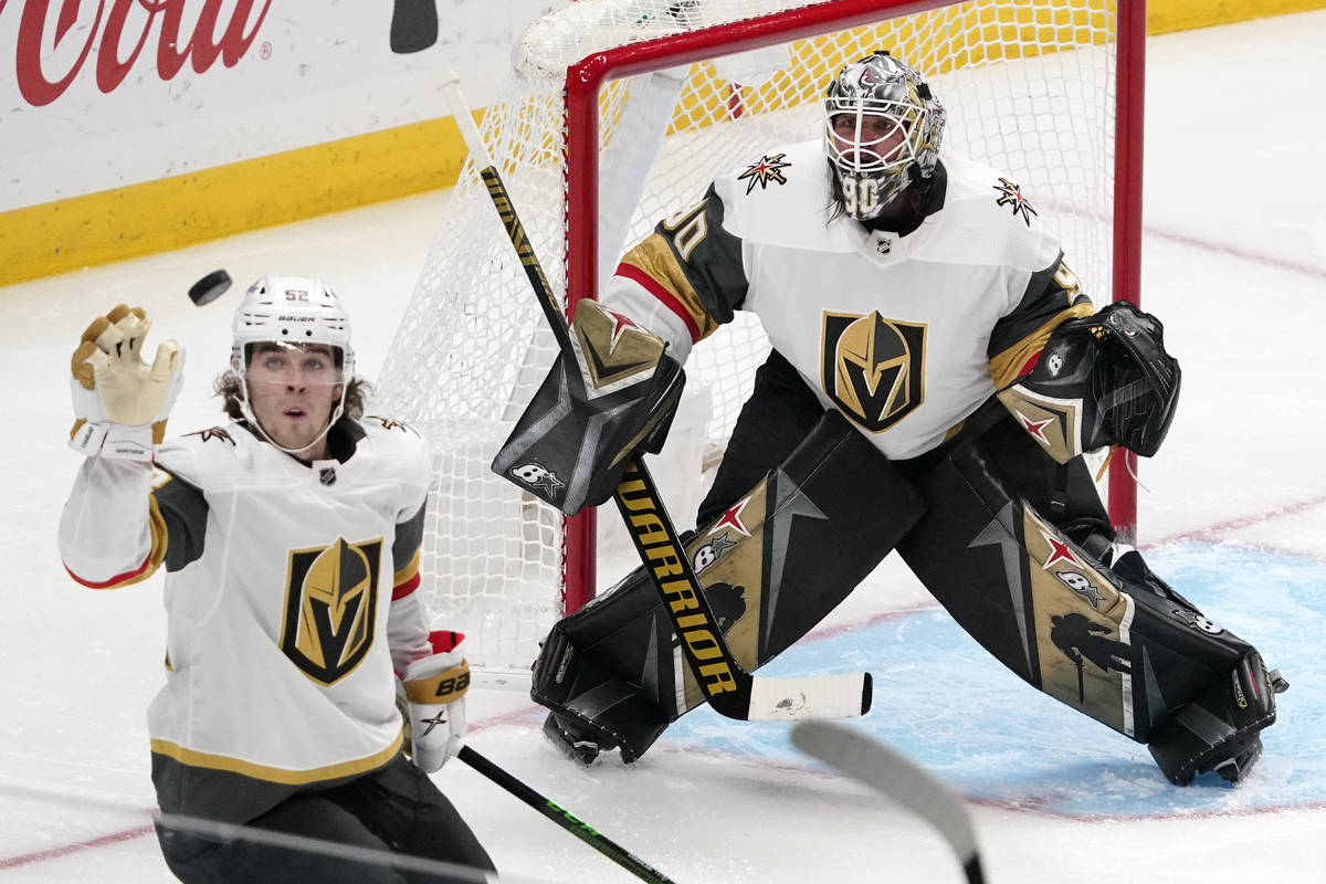 Vegas Golden Knights defenseman Dylan Coghlan, left knocks the puck out of the air as goaltende ...