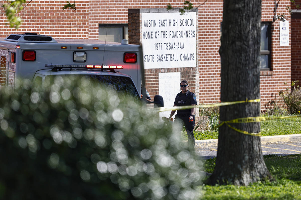 A member of the Knoxville police forensics team works the scene of a shooting at Austin-East Ma ...
