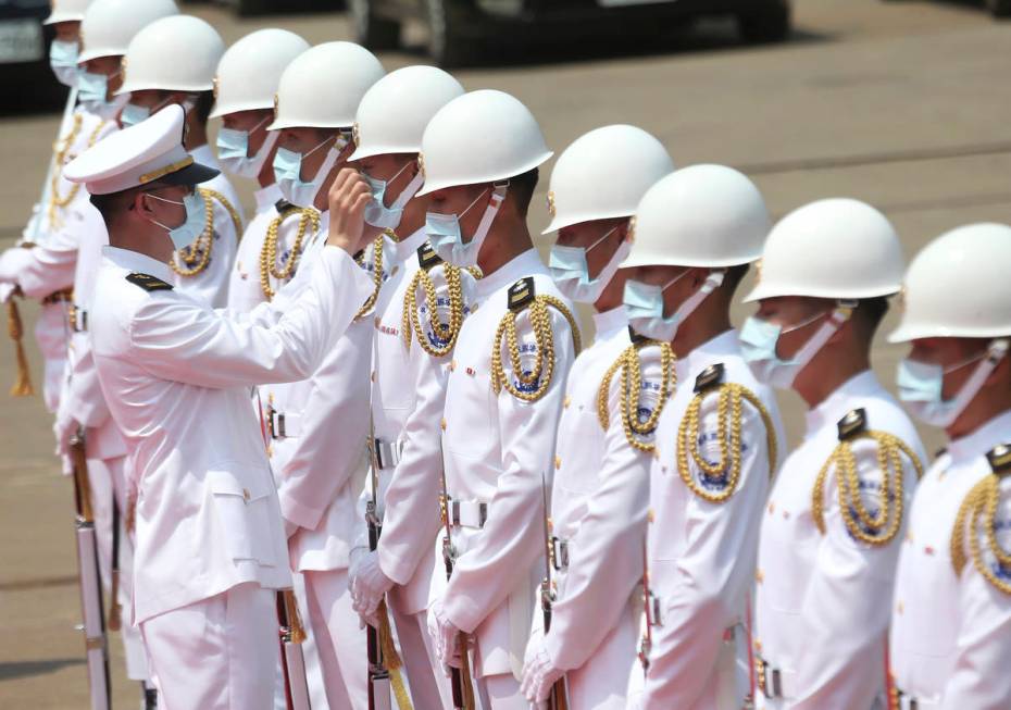 A Taiwan Navy honor guard captain adjusts team member's face mask during a launch ceremony for ...