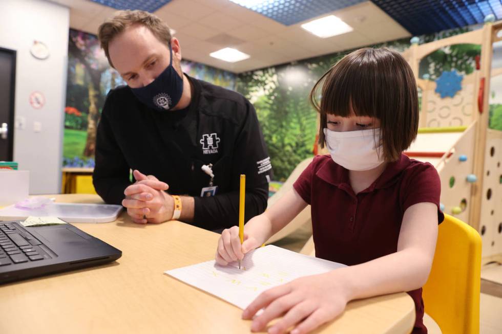 Akara Haase, 6, works with behavior analyst Adam Volker at the Center for Autism and Developmen ...