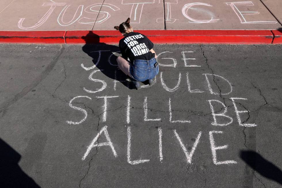 Jazz Appin writes messages in chalk on the ground outside the Clark County Government Center on ...