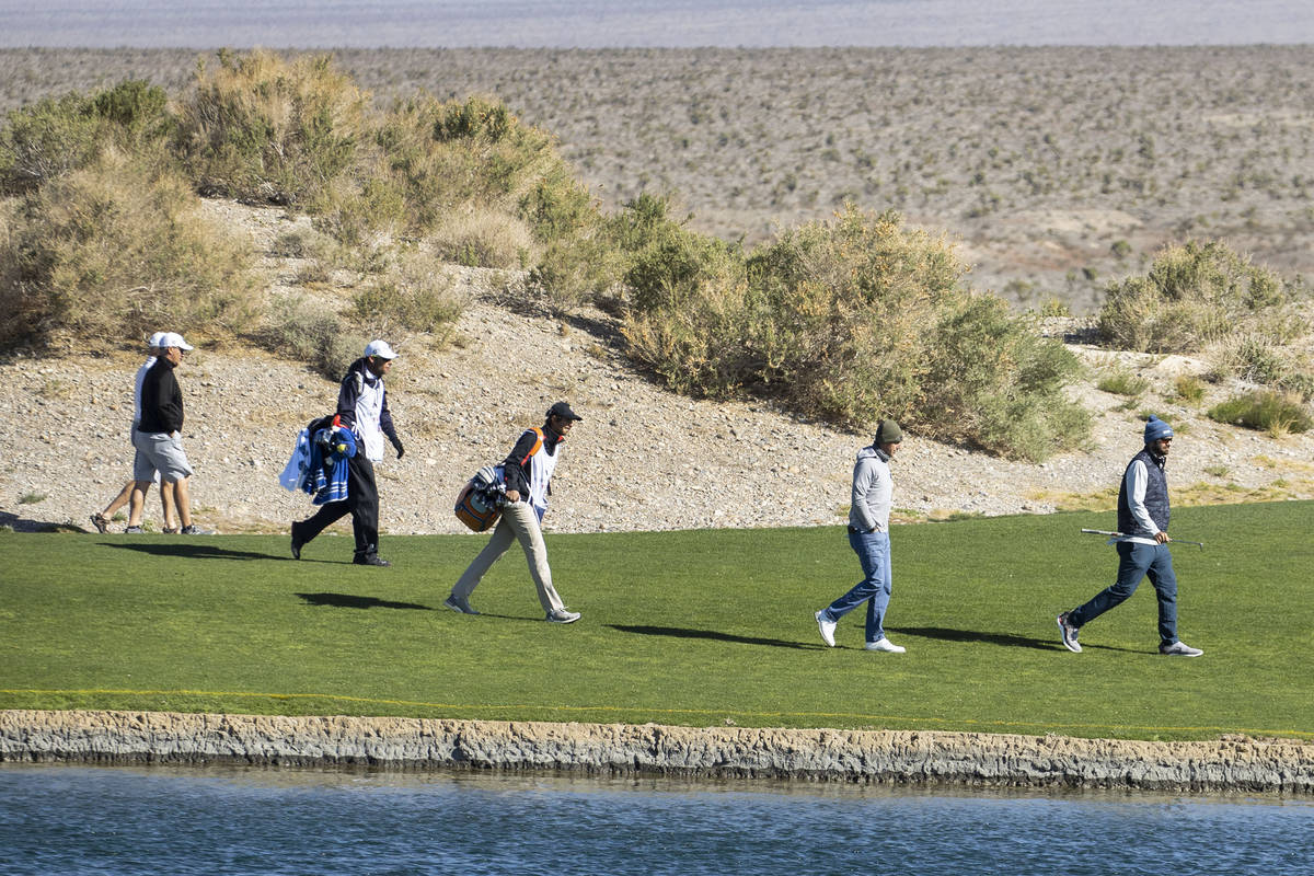 Triple-A golfers and their caddies walk past the pond during the first round of the MGM Champio ...