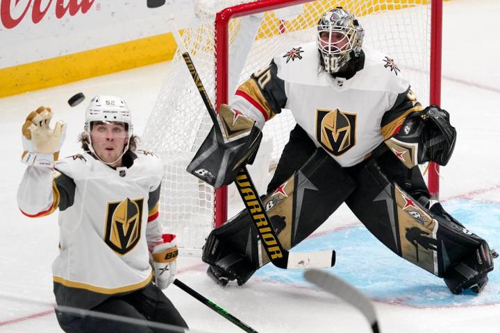 Vegas Golden Knights defenseman Dylan Coghlan, left knocks the puck out of the air as goaltende ...