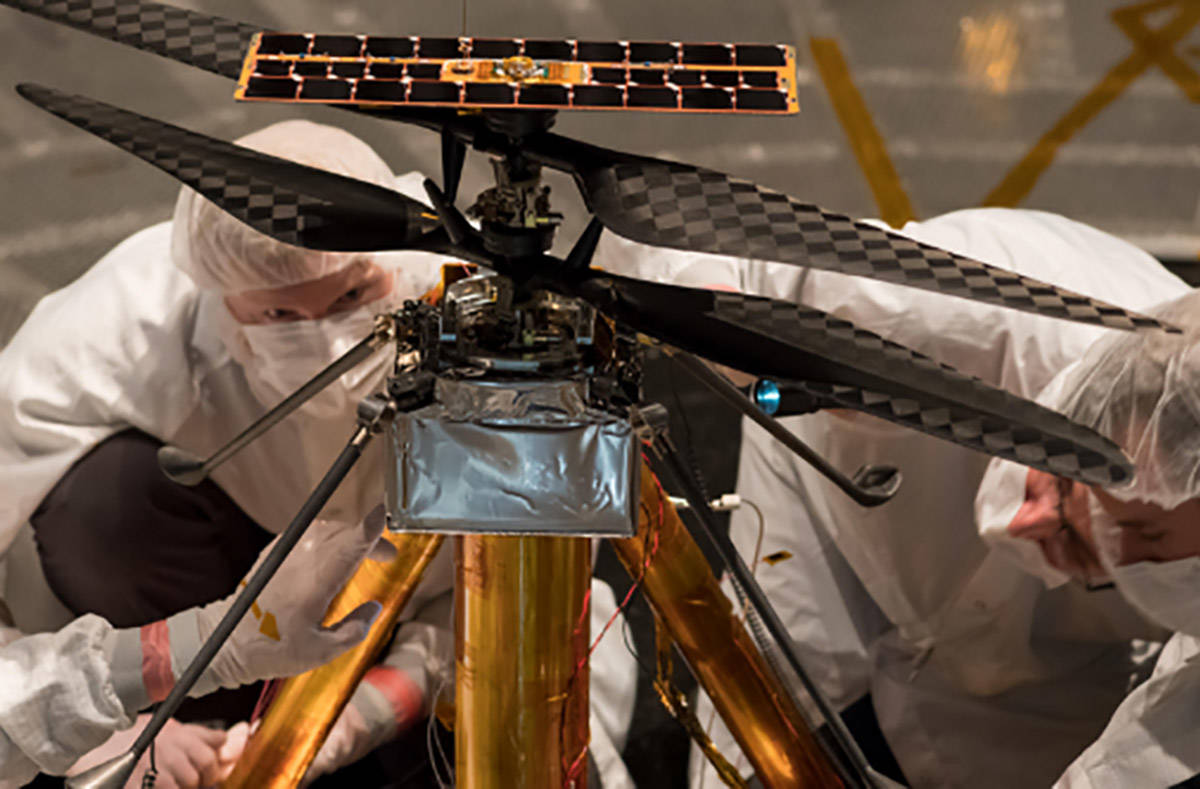 Members of the NASA Mars Helicopter team inspect the flight model (the actual vehicle going to ...