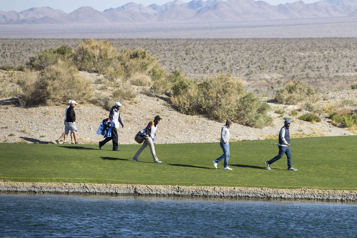 Triple-A golfers and their caddies walk past the pond during the first round of the MGM Champio ...