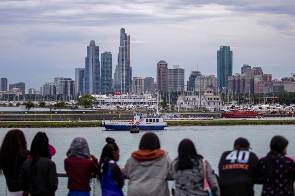 A group of people stand along Lake Michigan as they view Chicago's skyline from Navy Pier, Frid ...