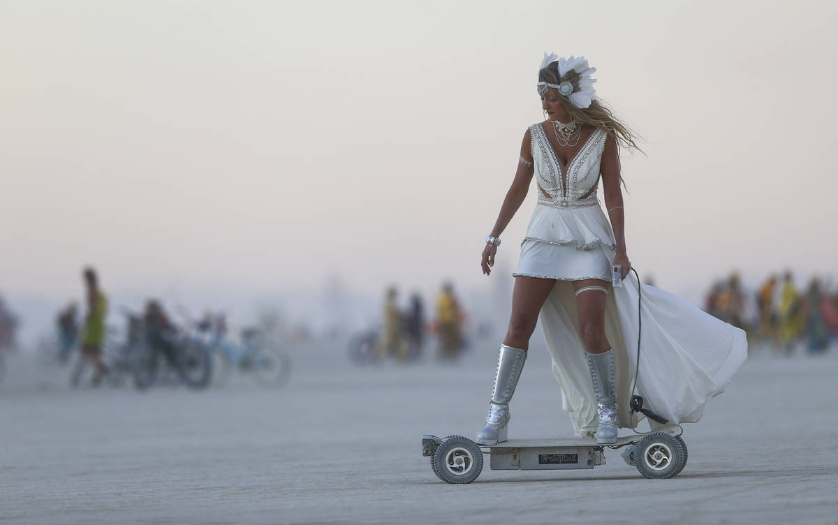 A woman rides an electric scooter during Burning Man at the Black Rock Desert north of Reno on ...