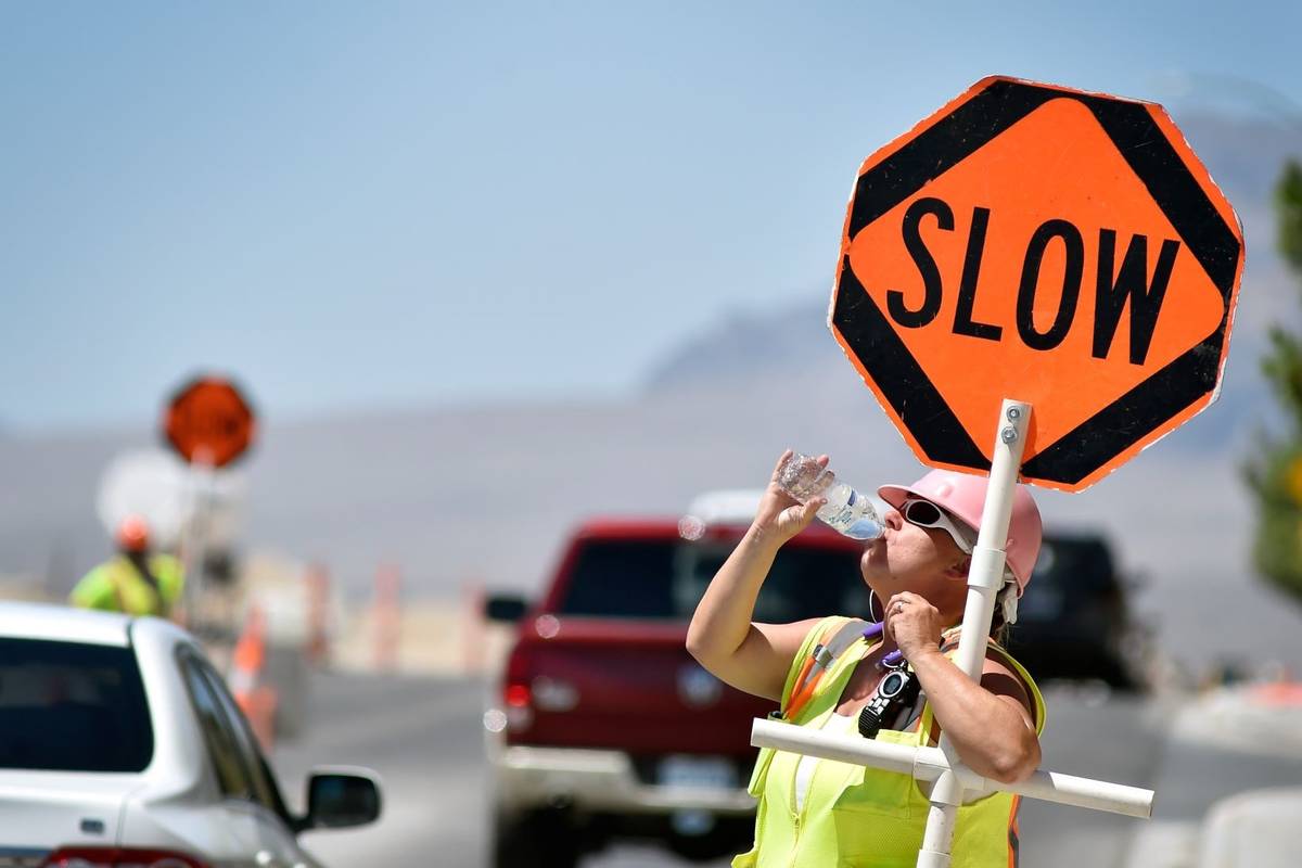 Flagger Shayne Boley guides vehicles though a construction zone on North Grand Canyon Drive in ...