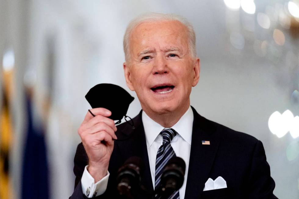 In this March 11, 2021, file photo President Joe Biden holds up his mask as he speaks about the ...