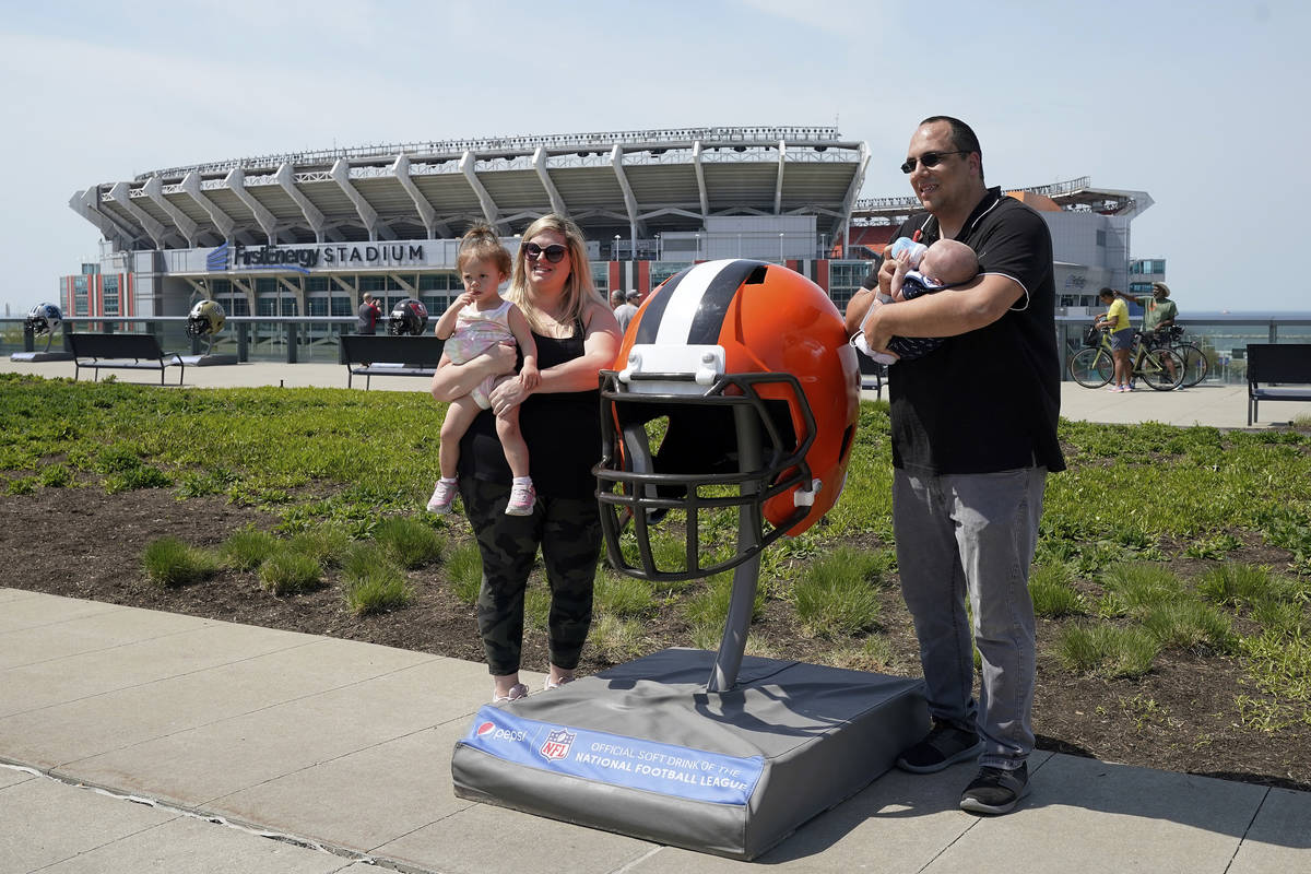 Fans pose for a photo with a large Cleveland Browns helmet, Tuesday, April 27, 2021, in Clevela ...