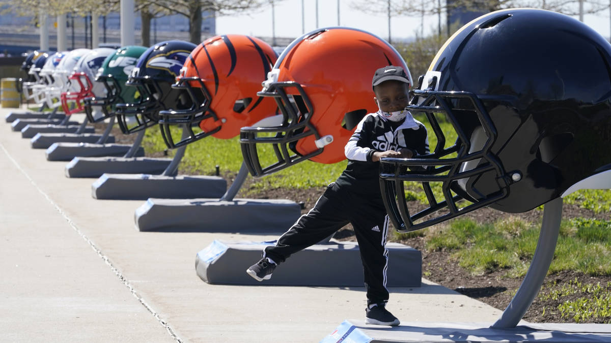 Joseph Toliver, 4, plays on one of the 32 NFL team helmets on display, Tuesday, April 13, 2021, ...
