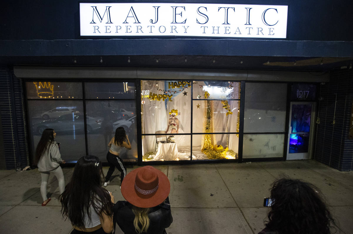 Passersby watch as Heidi Rider performs from the windows of the Majestic Repertory Theatre in t ...