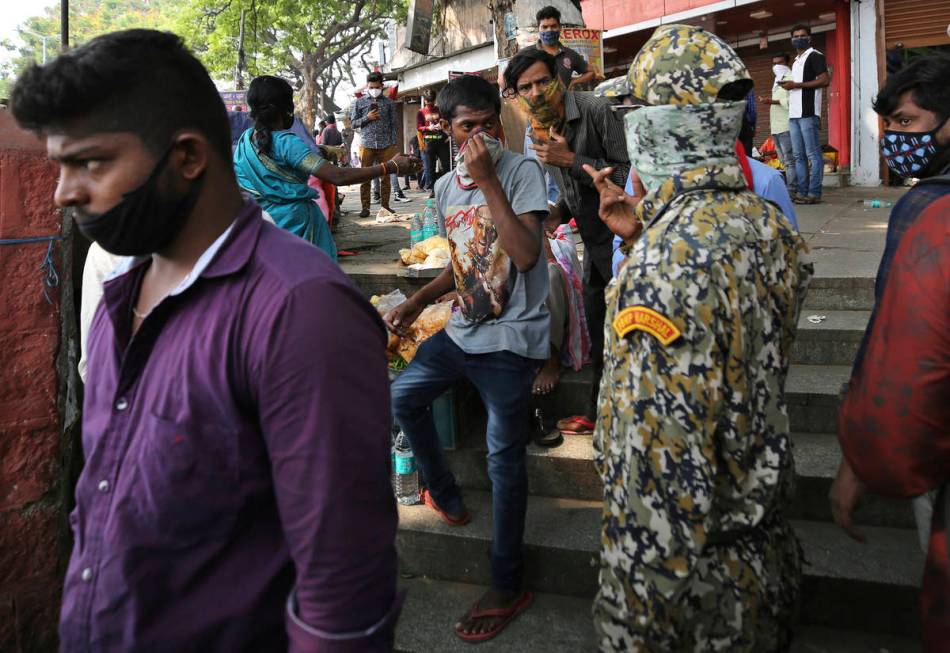 A municipal official, second right, reprimands street vendors for not wearing face masks proper ...