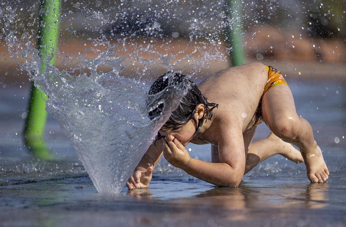 Bodhi Brown, 5, grabs his nose as he crawls into a fountain while playing in the water park at ...