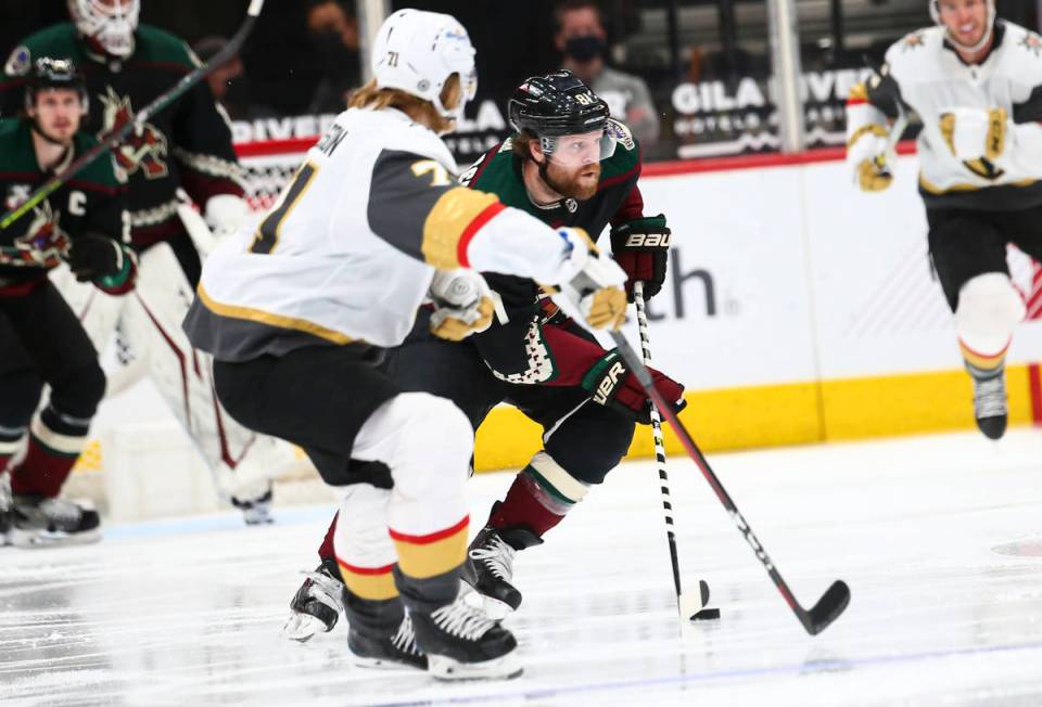 Arizona Coyotes' Phil Kessel (81) skates with the puck under pressure from Golden Knights' Will ...