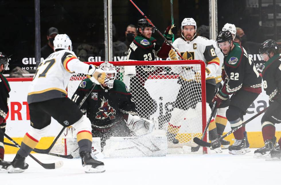 Arizona Coyotes goaltender Adin Hill (31) and forward Johan Larsson (22) defend the net as Gold ...