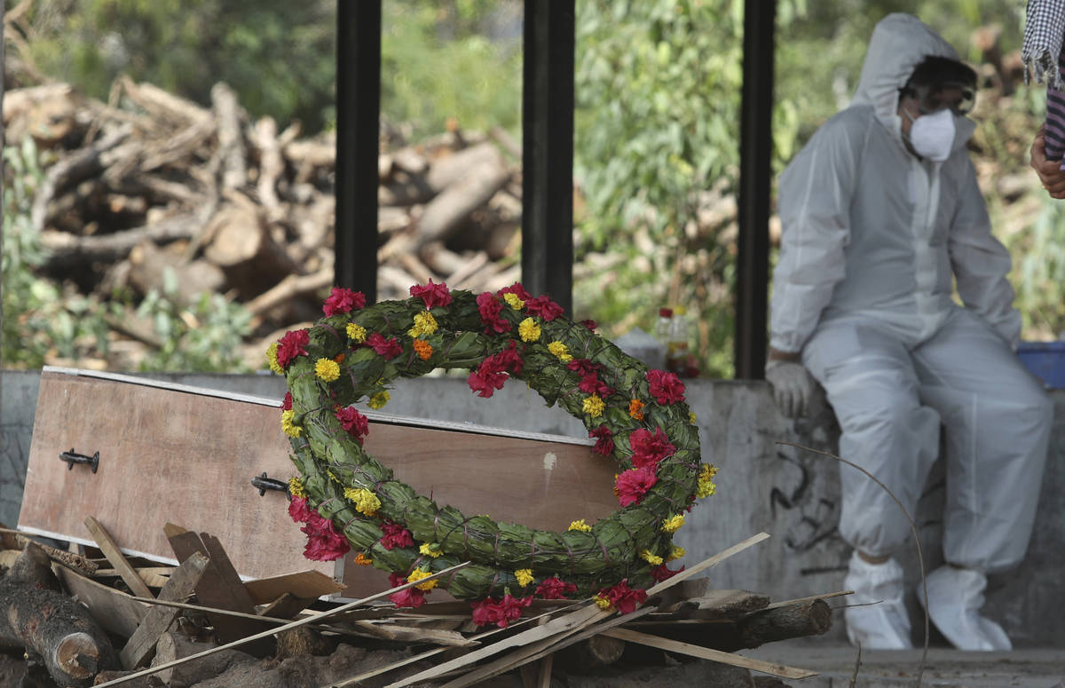 A wreath lies on the coffin of a COVID-19 victim before his cremation in Jammu, India, Friday, ...