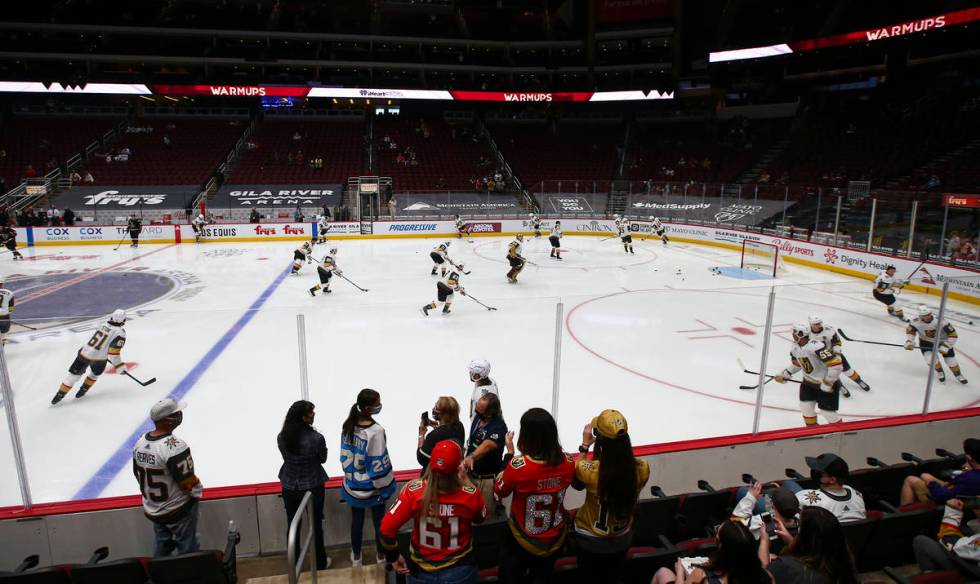 Golden Knights fans watch as players warm up before an NHL hockey game against the Arizona Coyo ...