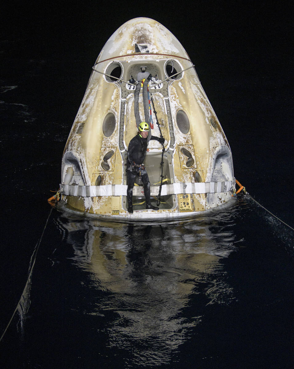Support teams work around the SpaceX Crew Dragon Resilience spacecraft shortly after it landed ...