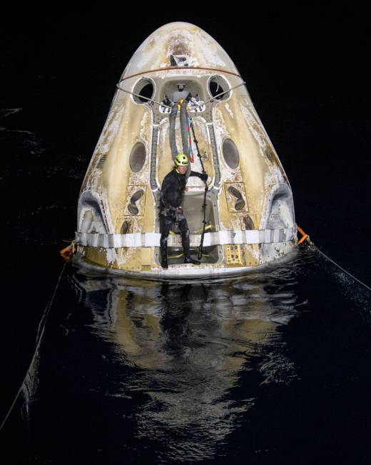 Support teams work around the SpaceX Crew Dragon Resilience spacecraft shortly after it landed ...