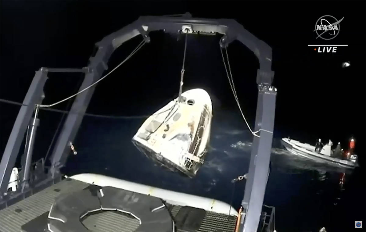 In this image made from NASA TV video, the SpaceX Dragon capsule is retrieved from the Gulf of ...