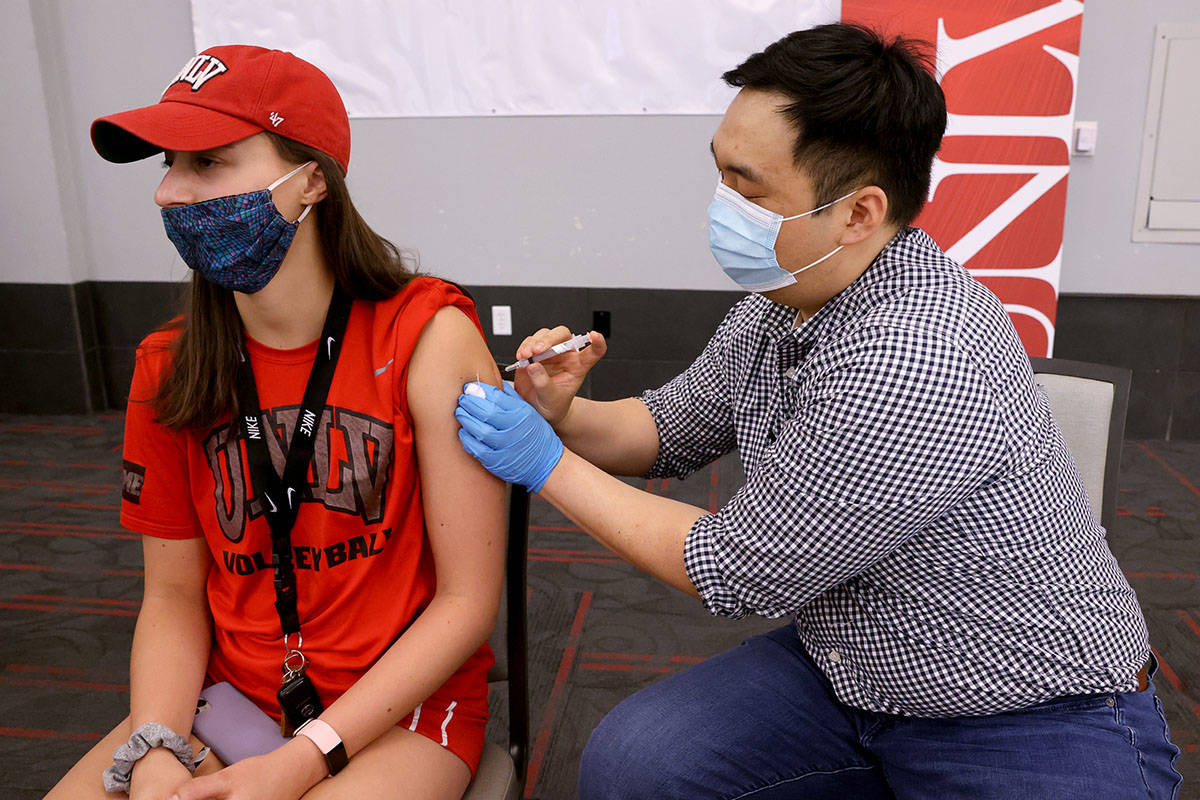 UNLV volleyball player Kate Brennan, 20, gets a COVID-19 vaccination from Andrew Choi at the UN ...