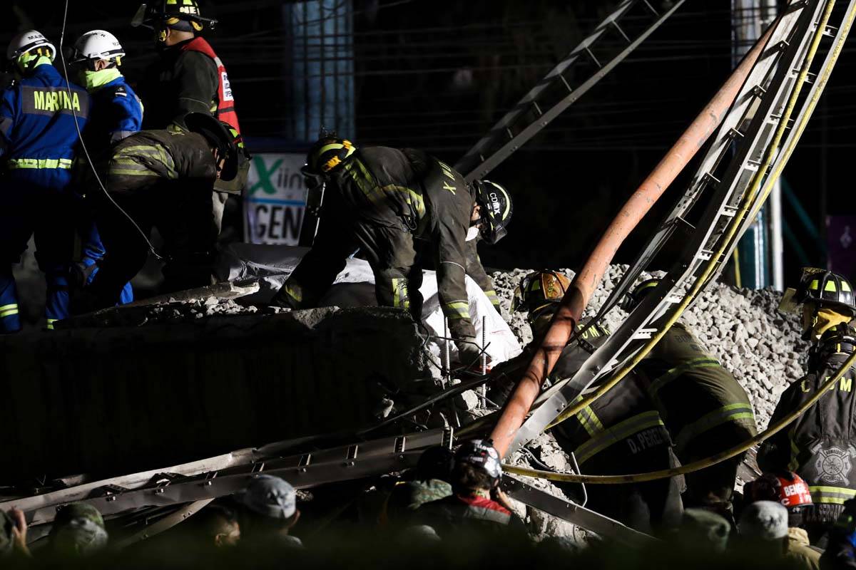 Rescue personnel retrieve bodies from the scene of an accident where subway cars fell after a s ...
