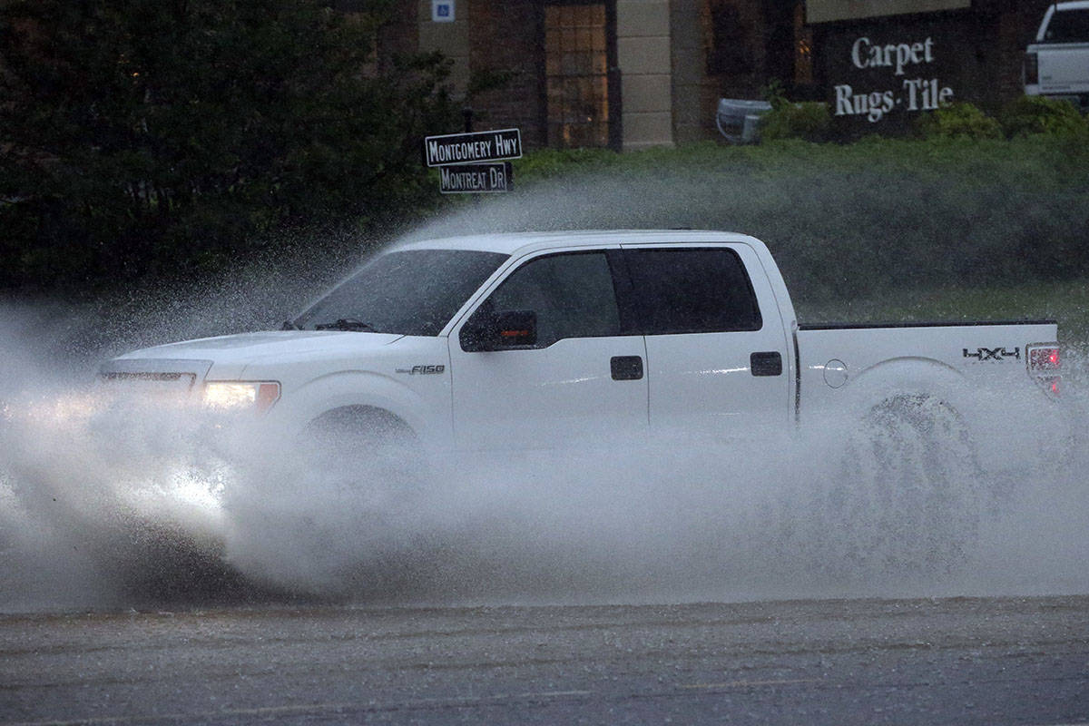 A pickup truck travels along a flooded road as severe weather produces torrential rainfall, Tue ...