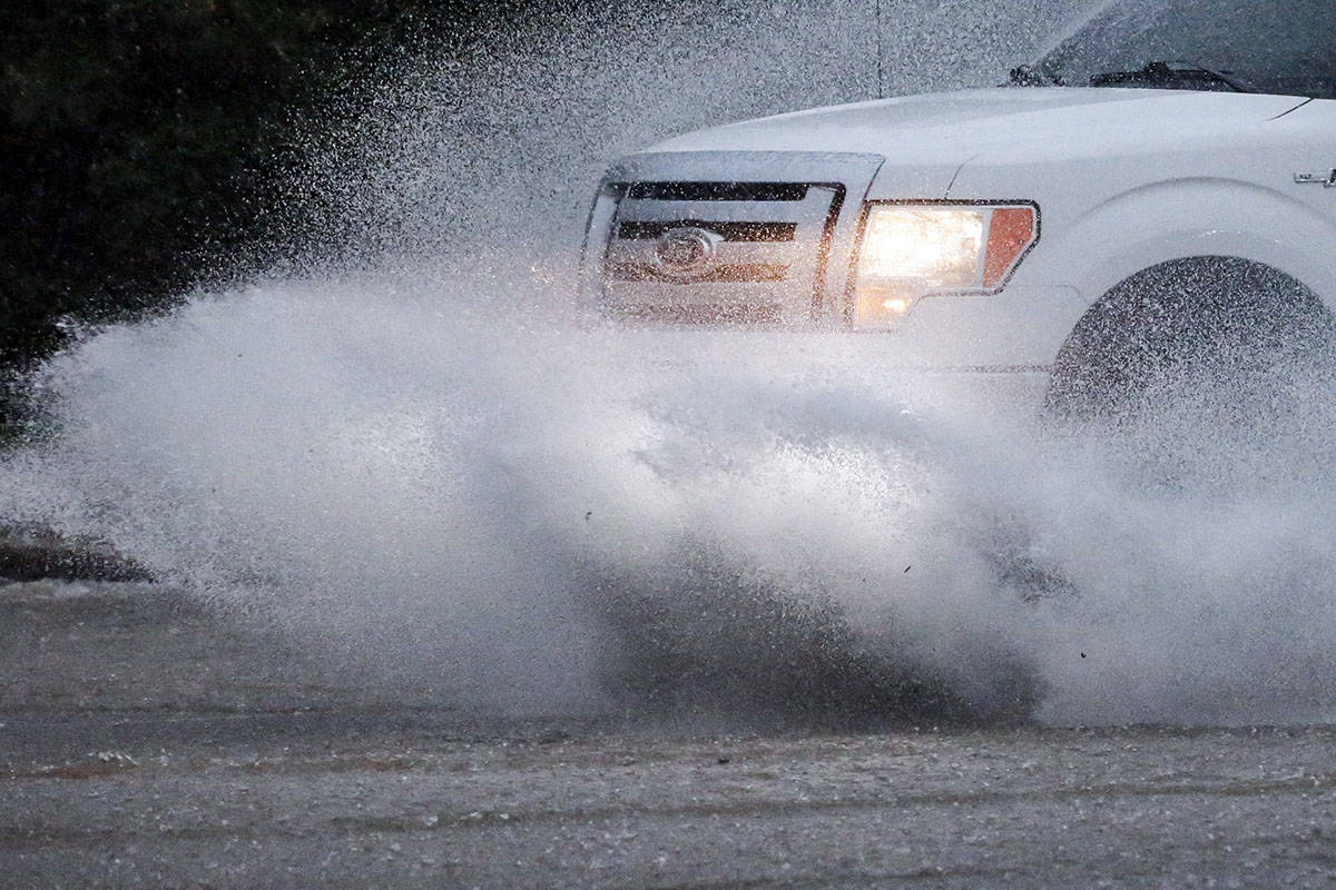 A vehicle travels along a flooded road as severe weather produces torrential rainfall, Tuesday, ...