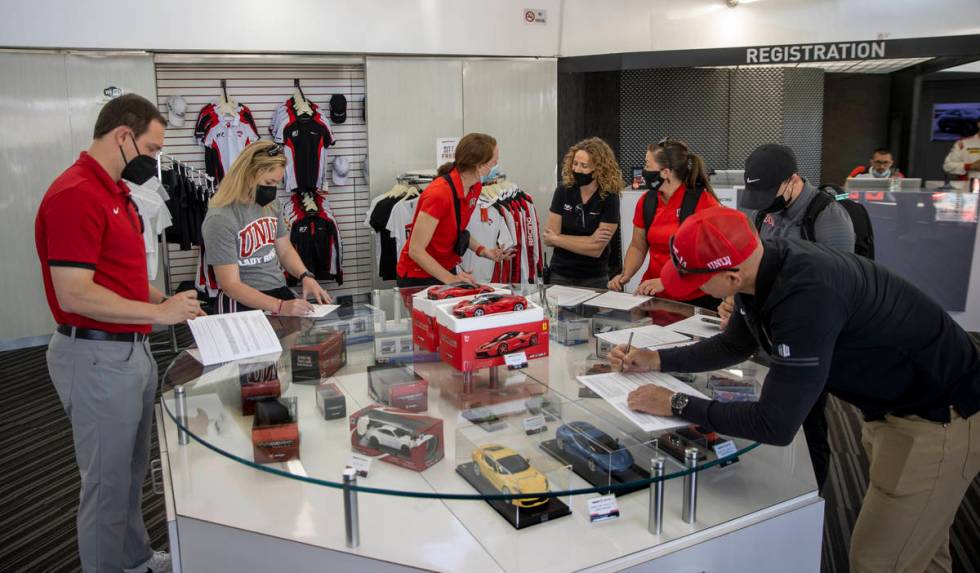 UNLV coaches fill out paperwork as they bring their Rebel Caravan to Dream Racing at the Las Ve ...
