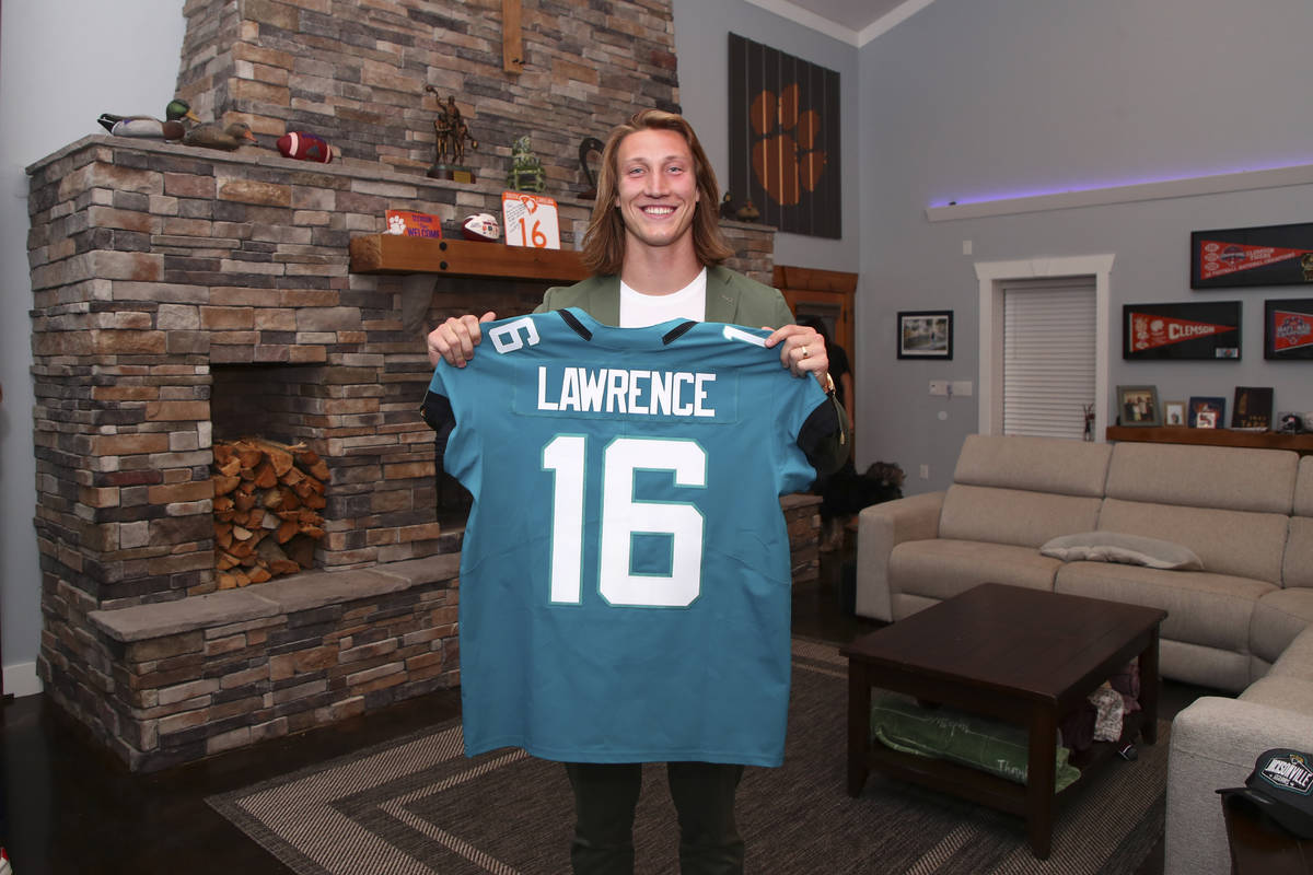 Clemson quarterback Trevor Lawrence holds up a jersey after being selected by the Jacksonville ...