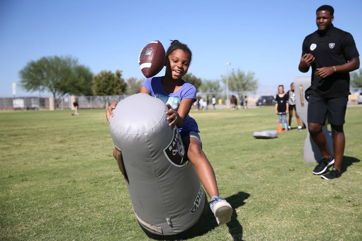 Third grade student Camille Jones, 8, left, participates in a Raiders youth football camp at Ro ...