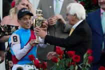 Trainer Bob Baffert hands the winner's trophy to jockey John Velazquez after they victory with ...