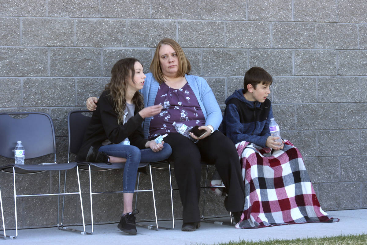 A woman and children sit together at the high school where people were evacuated after a shooti ...