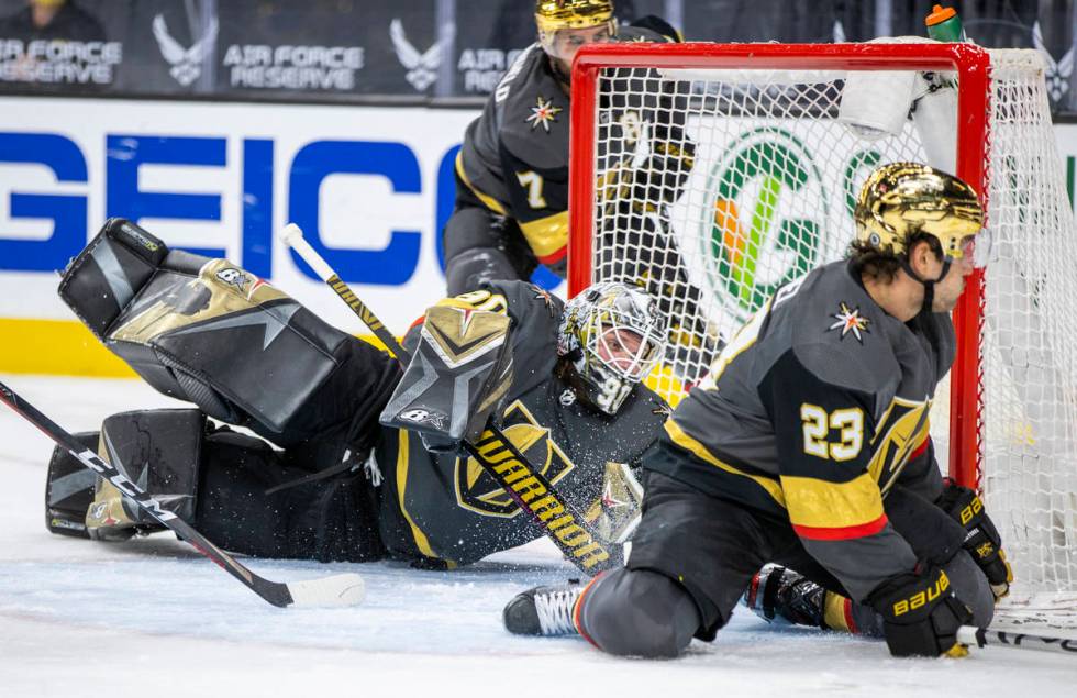 Golden Knights goaltender Robin Lehner (90) teams up to defend the net with defenseman Alec Mar ...