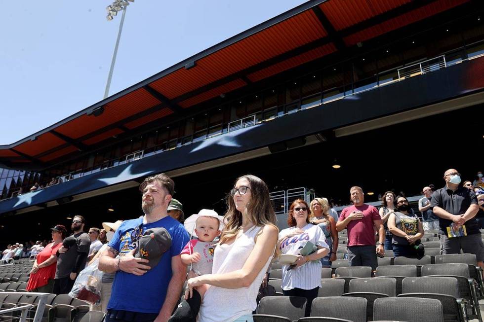 Kelsey Law stands for the National Anthem with her son Chandler, 11 months, and husband Matt at ...