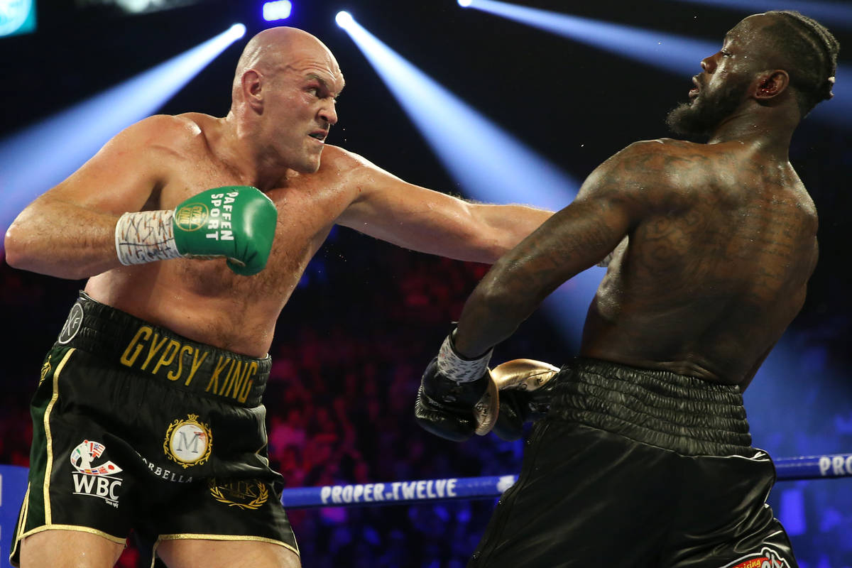 Deontay Wilder, below, slips under Tyson Fury in round 4 of the WBC world heavyweight champions ...